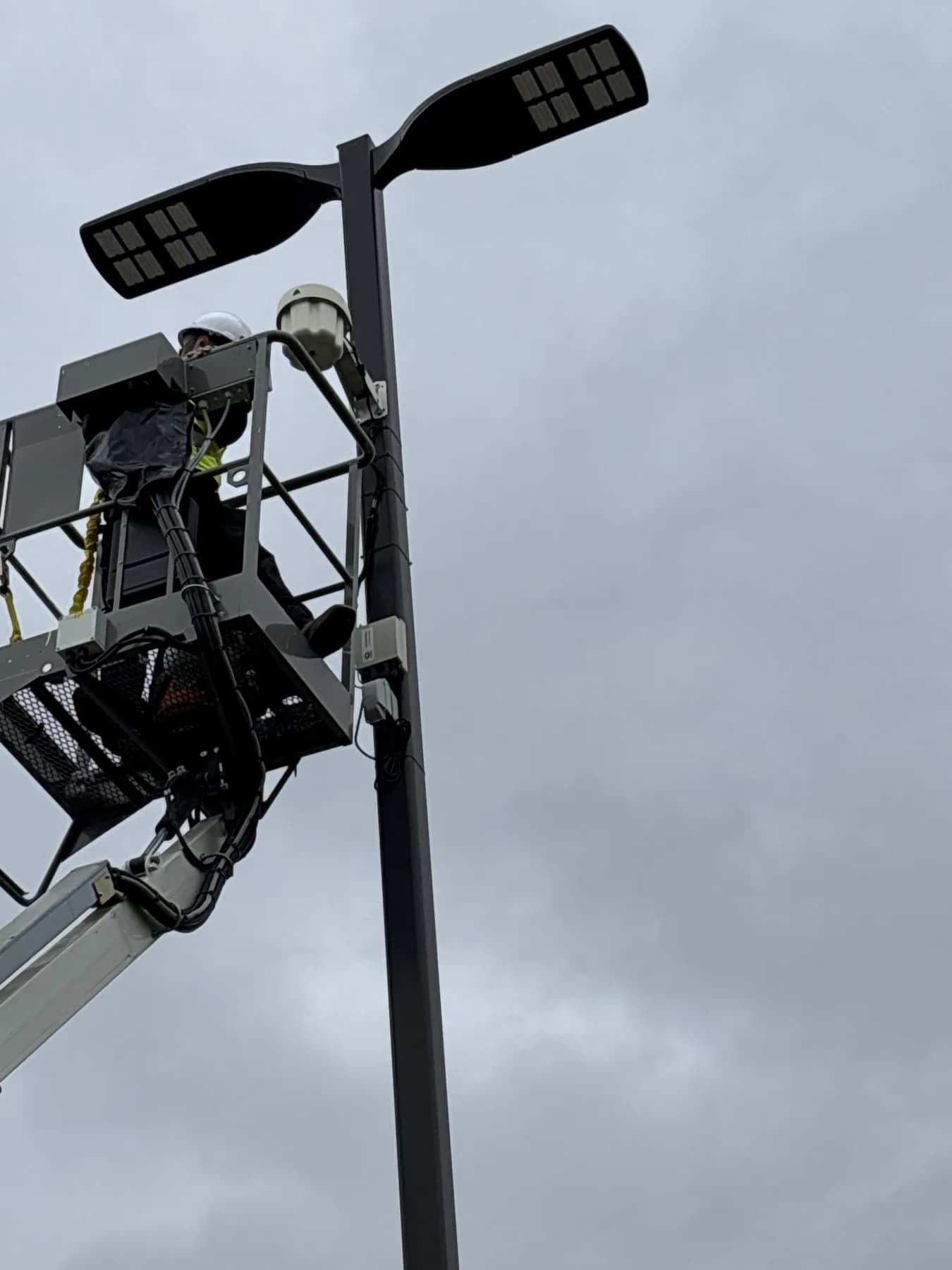 Technician in a lift installing an exterior wireless access point on a light pole