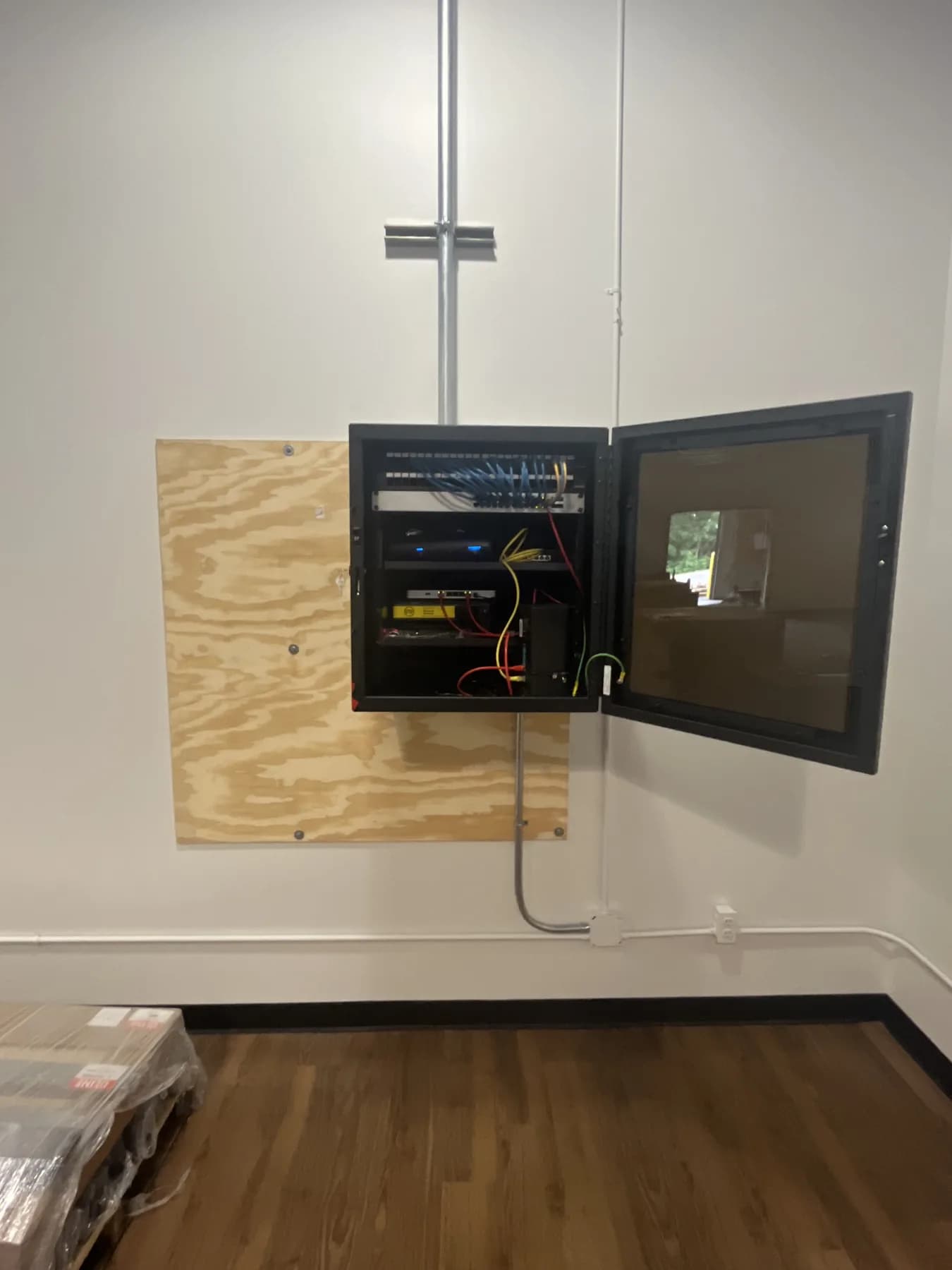 Wall-mounted commercial network cabinet with conduit and terminated cabling